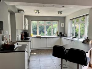 a large kitchen with white cabinets and black counter tops at Pass the Keys Charming 3 bed house with parking and large garden in Radlett