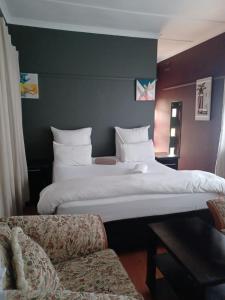 a hotel room with two beds and a couch at Mino Guest House in Pietermaritzburg