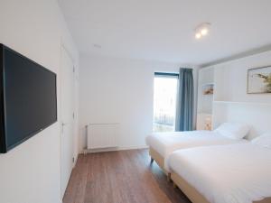 1 dormitorio con 2 camas y TV de pantalla plana en Modern wellness lodge with sunshower in a national park, en Tholen