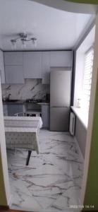 cocina con armarios blancos y suelo de mármol en Просторная квартира в центре Тирасполя! en Tiraspol