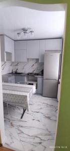 cocina con armarios blancos y suelo de mármol en Просторная квартира в центре Тирасполя!, en Tiraspol