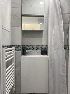une cuisine blanche avec un évier et un miroir dans l'établissement AgíaHouse - Aubervilliers, à Aubervilliers