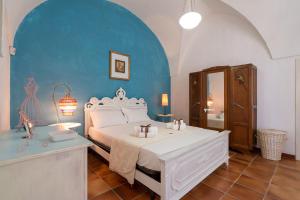Villa Boschetti Apartments في مونوبولي: غرفة نوم بسرير ابيض وجدار ازرق
