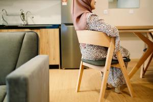 uma mulher sentada numa cadeira numa cozinha em Mahkota Valley Suite by Timorra em Kuantan