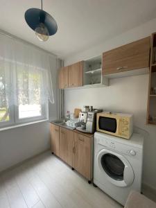 a kitchen with a washing machine and a microwave at Apartament Orșova Faleză in Orşova
