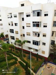 un bâtiment blanc avec des palmiers devant lui dans l'établissement Appartement agadir, à Agadir