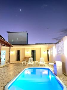 uma piscina em frente a uma casa com um grande ecrã em Chalés Sol de Milagres em São Miguel dos Milagres