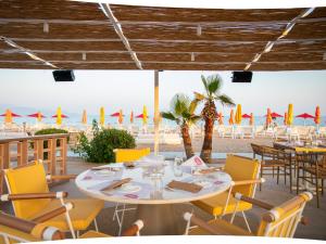 ein Restaurant mit Tisch und Stühlen und Strand in der Unterkunft Buka Sandy Beach in Messini