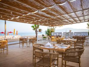 ein Restaurant am Strand mit Tischen und Stühlen in der Unterkunft Buka Sandy Beach in Messini
