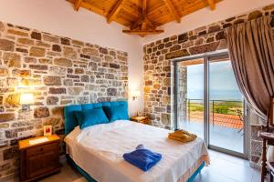 a bedroom with a bed with a stone wall at Stonevillas and Seaview Garden Marion in Agnándion