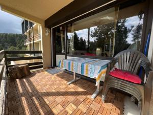 une terrasse couverte avec un banc et un lit sur un balcon dans l'établissement Les Camparoles, à Font-Romeu-Odeillo-Via