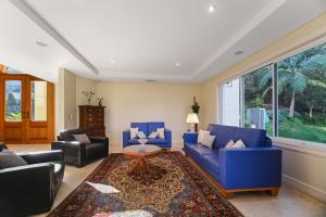 ein Wohnzimmer mit blauen Möbeln und einem großen Fenster in der Unterkunft House by the Harbor in Sydney