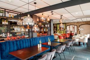 een restaurant met tafels en stoelen en kroonluchters bij Hotel De Oringer Marke & Stee by Flow in Odoorn
