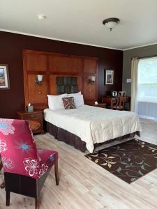 a bedroom with a large bed and a chair at Vinehurst Inn & Suites in Hammondsport