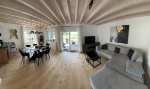 sala de estar con sofá y mesa con sillas en Chiemgau Ferienhaus Premium by BellaVita, en Bad Endorf