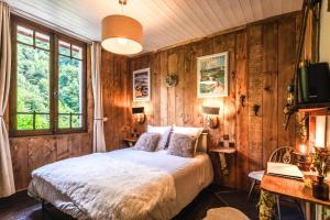 una camera da letto con pareti in legno, un letto e una scrivania di Les Ruisseaux a Cauterets