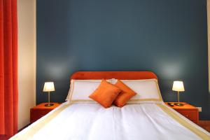 a bed with two orange pillows and a blue wall at Charming Vatican LargeApt by YH in Rome