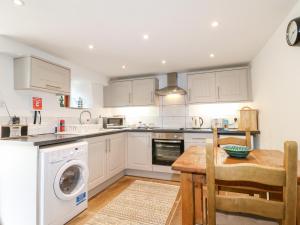 a kitchen with white cabinets and a table and a dishwasher at The Dell in Winster