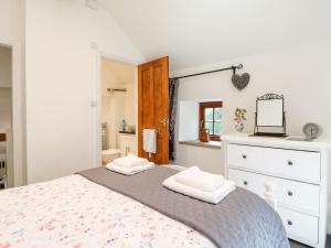 a bedroom with a bed with a dresser and a mirror at The Dell in Winster