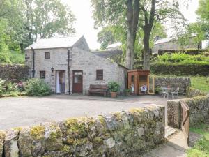 a stone cottage with a stone wall in front of it at The Dell in Winster