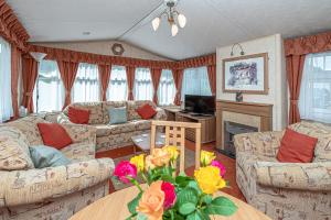 una sala de estar con sofás y una mesa con flores en Caravan at Ysgubor, en Tregarth