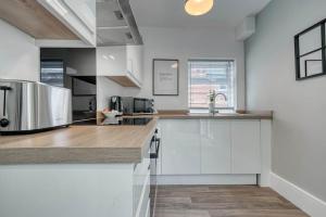 une cuisine avec des armoires blanches et un appareil en acier inoxydable dans l'établissement Stylish Home - Fast Wi-Fi-FREE Parking, à Nottingham