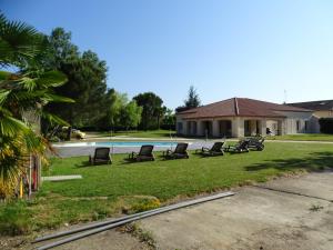 un grupo de sillas sentadas en el césped cerca de una piscina en chambres d'hôtes Villa Soleil, en Bergerac