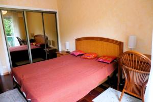 Schlafzimmer mit einem Bett mit roter Bettwäsche und roten Kissen in der Unterkunft Cosy cocoon with terrace near the sea in Arcachon