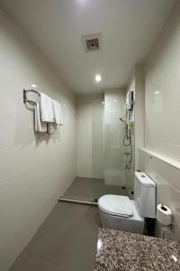 a white bathroom with a toilet and a shower at Phavina Hotel Rayong SHA Extra Plus in Rayong