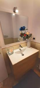 un lavandino in bagno con specchio e vaso di fiori di Casa Mia Sirolo a Sirolo