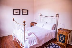1 dormitorio con cama blanca y mesa de madera en Oasis en Nieu-Bethesda