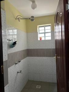 La salle de bains est pourvue d'une douche et d'une fenêtre. dans l'établissement Eclectic 2 bedrm homely & comfy, à Machakos
