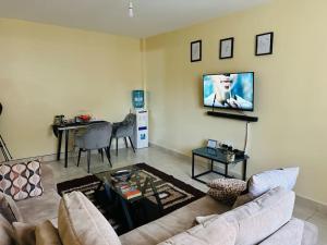 a living room with a couch and a tv on the wall at Eclectic 2 bedrm homely & comfy in Machakos