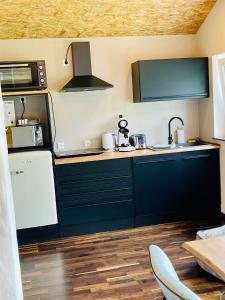 eine Küche mit schwarzen Schränken und einem weißen Kühlschrank in der Unterkunft Family Apartments Abuja in Rust