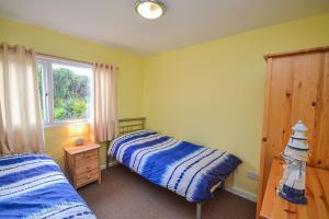 1 dormitorio con 2 camas y ventana en Tan Dinas Lodge en Benllech