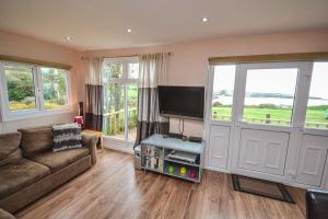 a living room with a couch and a flat screen tv at Tan Dinas Lodge in Benllech