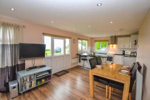 a living room with a table and a kitchen at Tan Dinas Lodge in Benllech