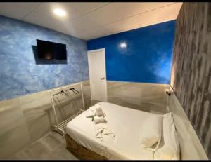 um quarto com uma cama com uma parede azul em Hostal Avenida Andalucia em Sevilha