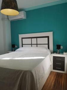 a bedroom with a white bed and a blue wall at Apartamento Tropical by Bossh! Apartments in Salobreña