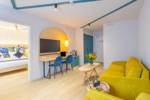 Una sala de estar con un sofá amarillo y una cama. en Urban Hotel & Spa Aix-les-Bains - BW Signature Collection, en Aix-les-Bains