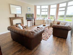 een woonkamer met 2 leren banken en een televisie bij The Retreat @ Wolds View in Bridlington