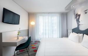 ベルリンにあるPark Plaza Berlinの白いベッドとテレビが備わるホテルルームです。