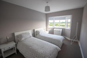 a bedroom with two beds and a window at Millbay View House in Kilkeel