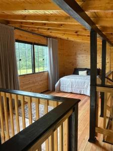 - une chambre avec un lit dans une cabane en bois dans l'établissement Cabana Luar da Serra, à Urubici