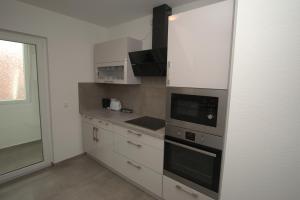 une cuisine avec des armoires blanches et un four à plaques de cuisson dans l'établissement AB Stuttgart Untertürkheim, à Stuttgart