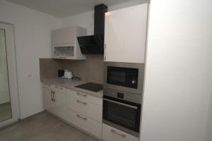 une cuisine avec des armoires blanches et un four à plaques de cuisson dans l'établissement AB Stuttgart Untertürkheim, à Stuttgart