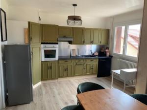 a kitchen with green cabinets and a table and a dining room at Cocon proche centre ville in Embrun