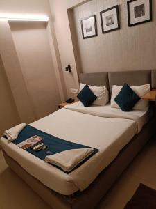 a bedroom with a large bed with blue pillows at Hotel Mayfair Tower in Kolkata