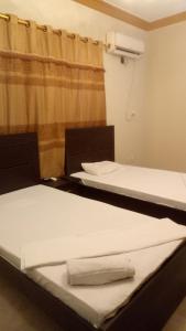 2 camas sentadas en una habitación con cortina en Johar Hill view Guest House, en Karachi