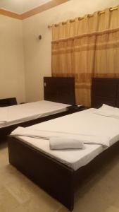 2 Betten nebeneinander in einem Zimmer in der Unterkunft Johar Hill view Guest House in Karatschi